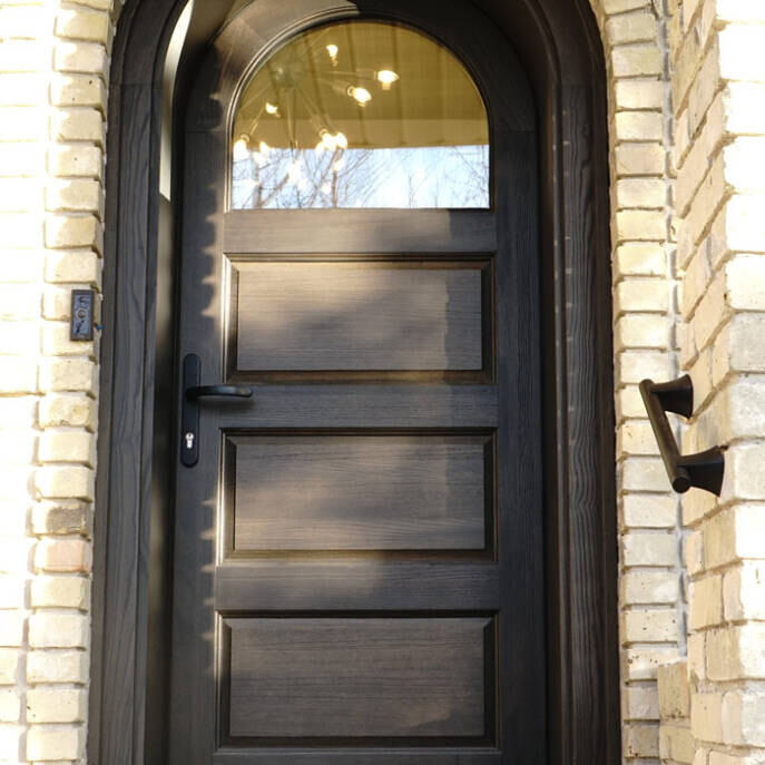 Beautiful dark brown wooden entrance door in brick house